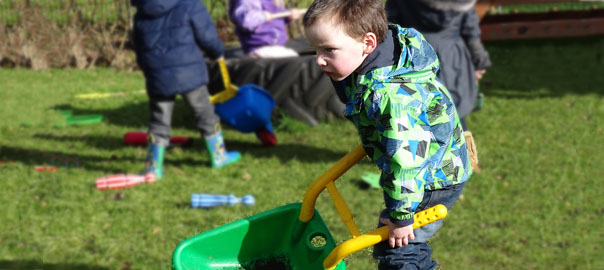 Child pushing a toy wheelbarrow
